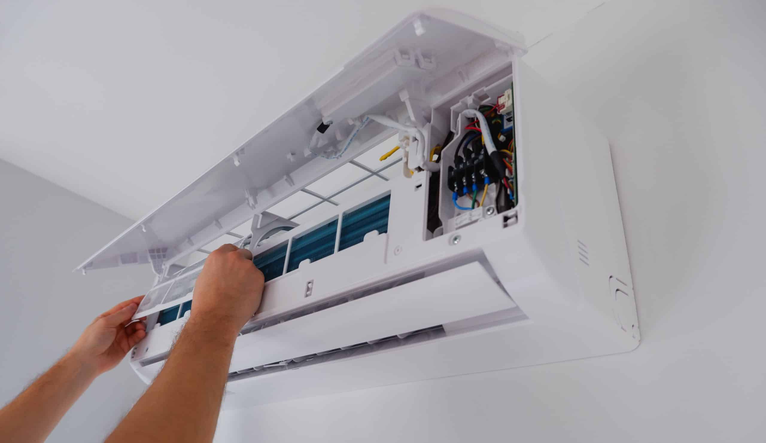 Air conditioner repair and maintenance. The technician removes the filter of the indoor unit for cleaning.