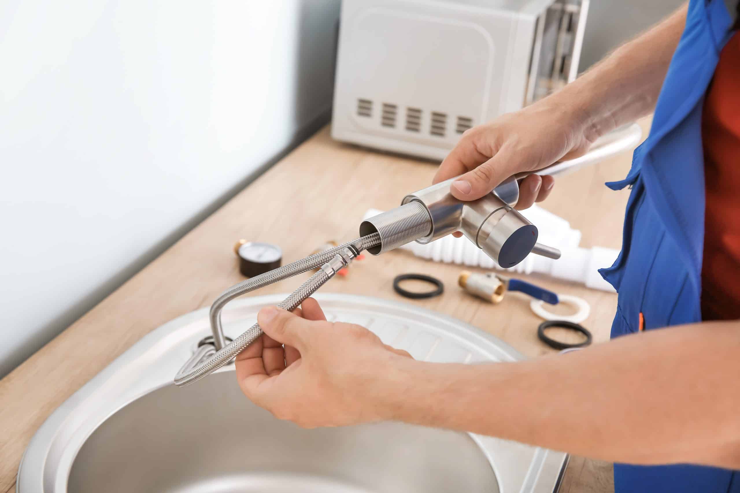 Plumber installing sink in kitchen
